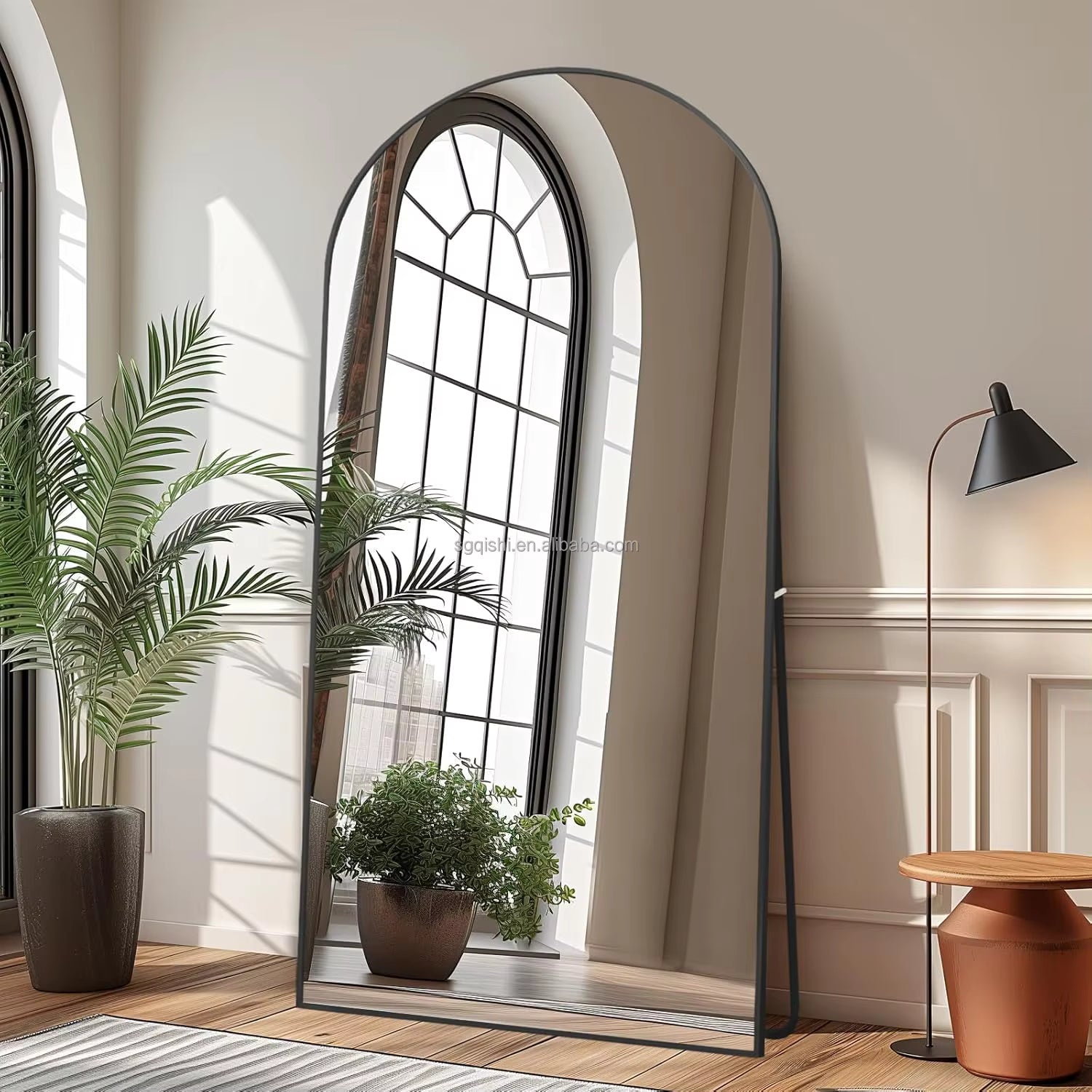 Arched floor mirror in a room with plants and a lamp